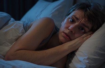 Person lying in bed, unable to sleep.